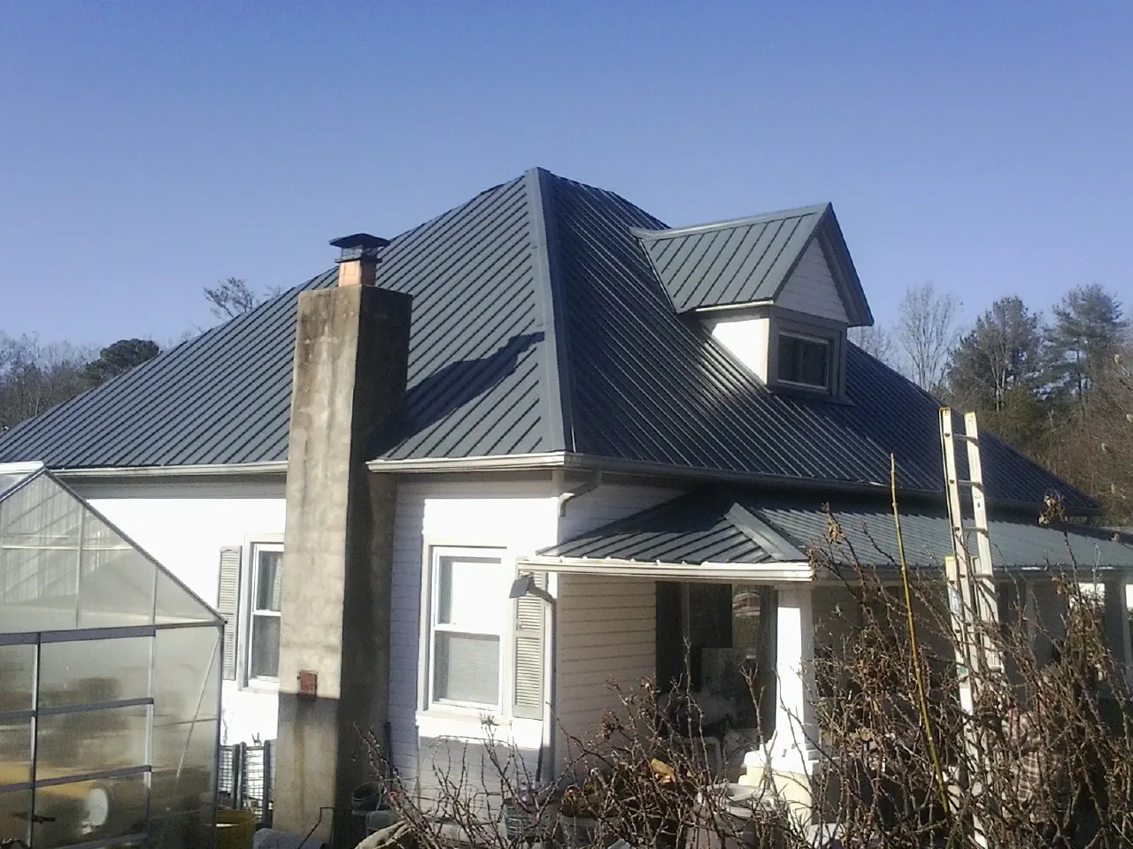 Dark blue standing seam metal roof on a white farmhouse with dormer — Slate & Tile Roof Repair by Roofing Brothers in Claymont