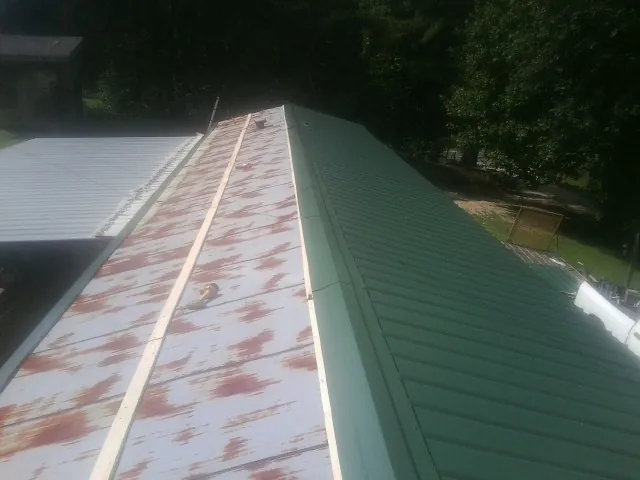 Old rusted panels beside newly installed green metal roofing — Wind Damage Roof Repair by Roofing Brothers in Claymont