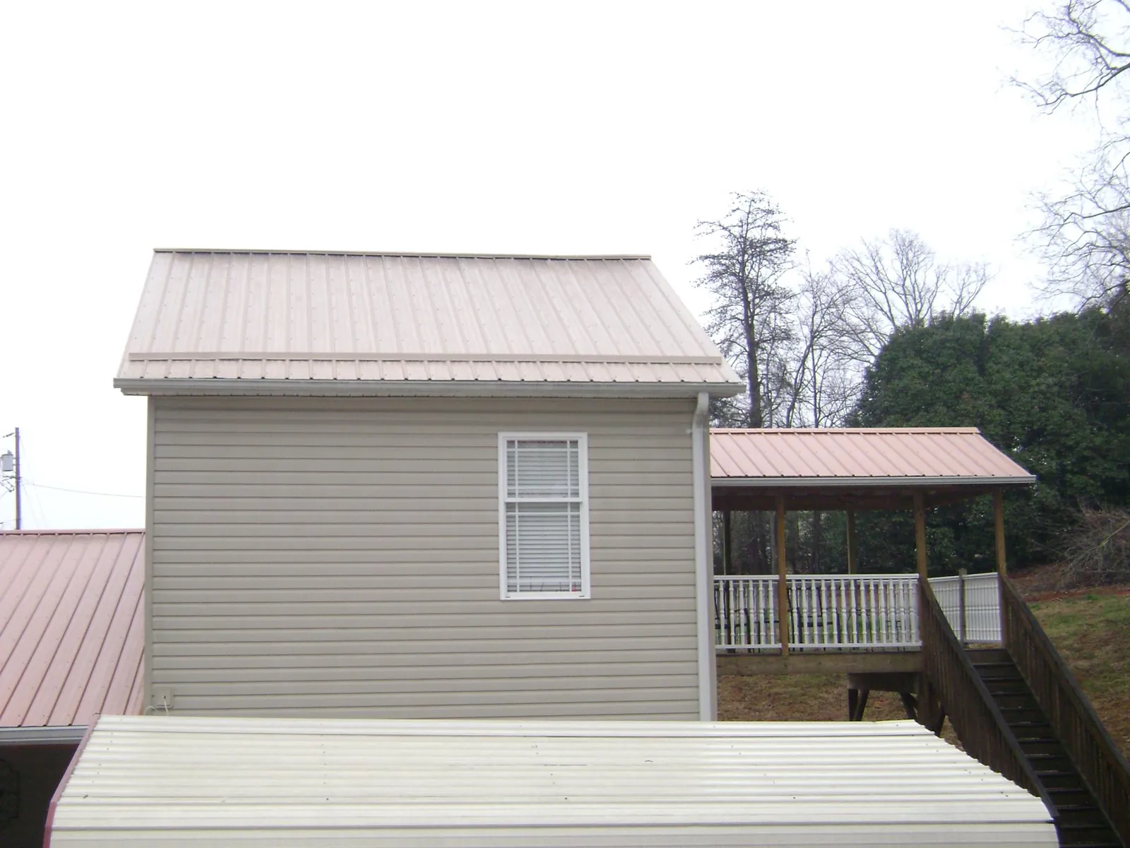 Tan metal roofs on a two story addition and attached porch, from a Roof Replacement job in Claymont