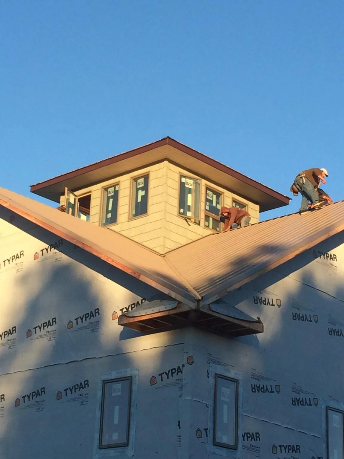 Roofers working around a rooftop cupola on a new metal roof at sunset — Roof Waterproofing in Claymont by Roofing Brothers